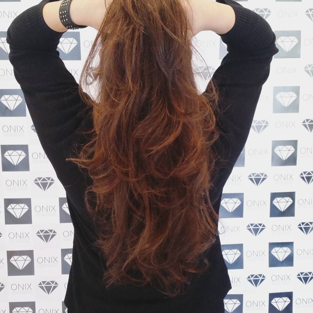 Pelo cobrizo largo con ondas, de espaldas frente a la pared de ONIX