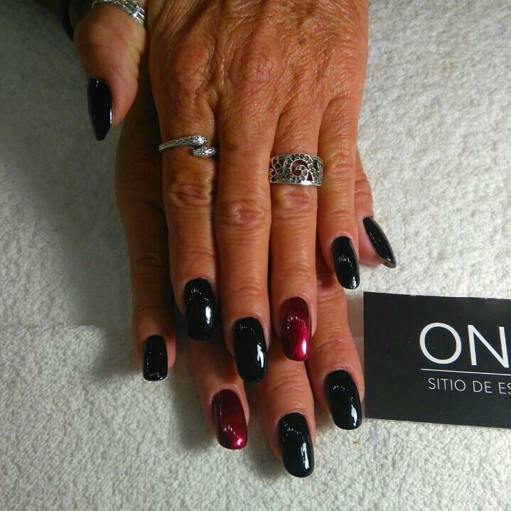 Uñas esmaltadas en negro y rojo sobre una toalla blanca, junto a una tarjeta de ONIX